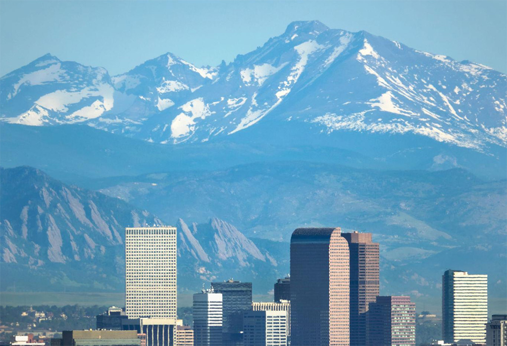 Downtown Denver skyline with Rocky Mountains in the background representing local business competition